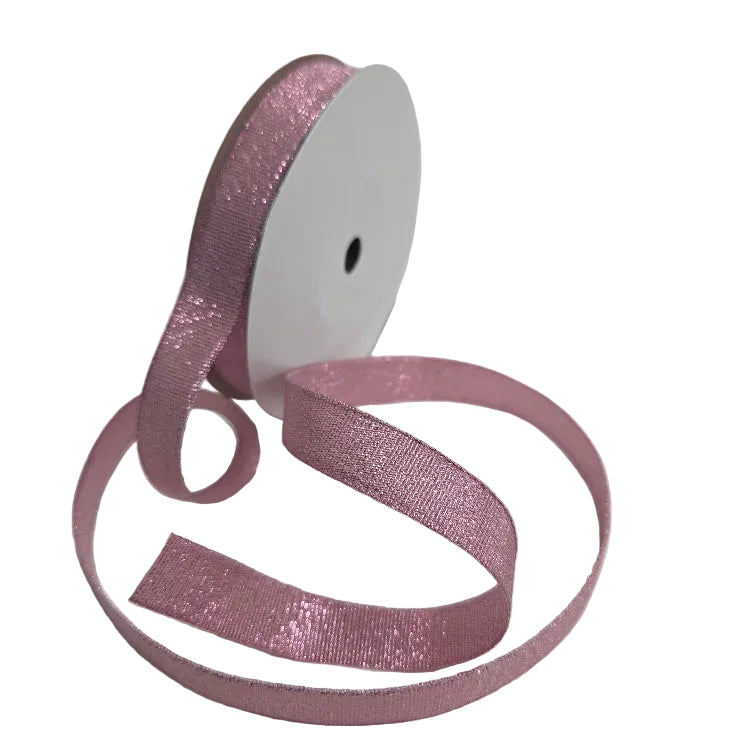 Pink glitter ribbon on a white spool against a white background