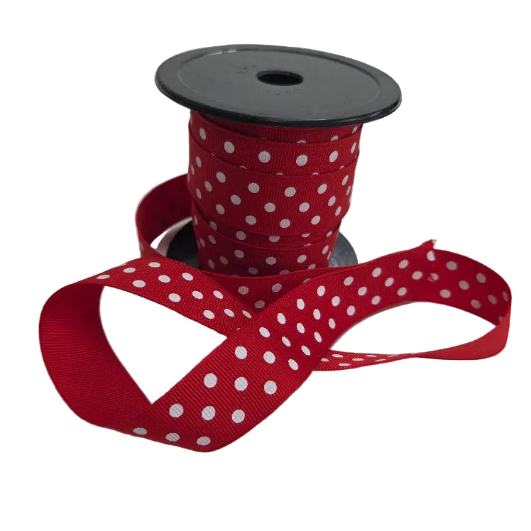 Spool of red ribbon with white polka dots on a white background