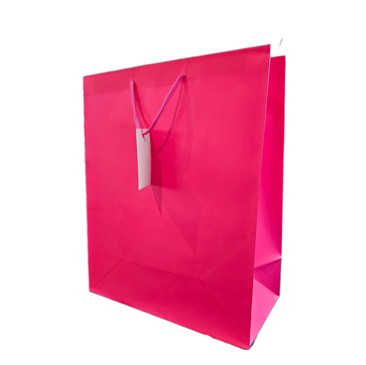 A bright hot pink paper shopping bag with purple rope handles and a blank white hangtag, shown on a solid white background.