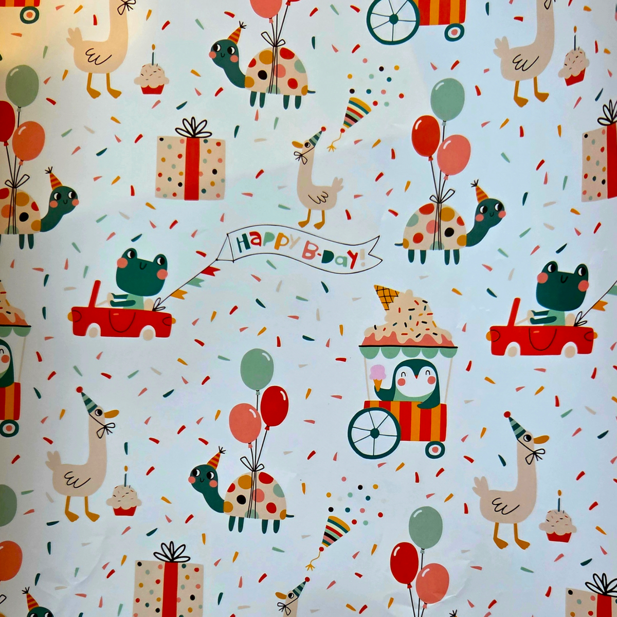 Children's birthday-themed wrapping paper with cartoon animals and objects.