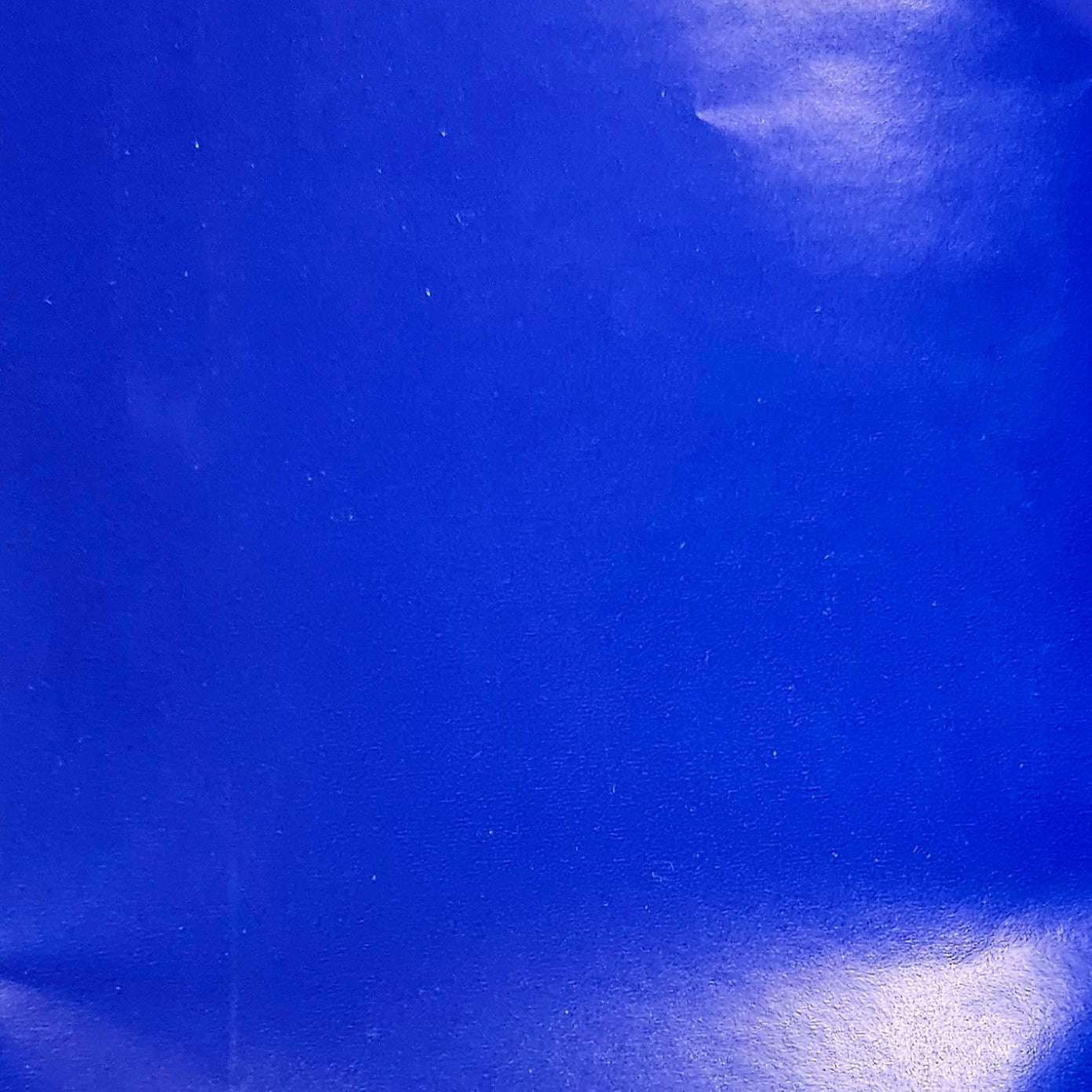 A close-up of a solid royal blue wrapping paper with a glossy finish.
