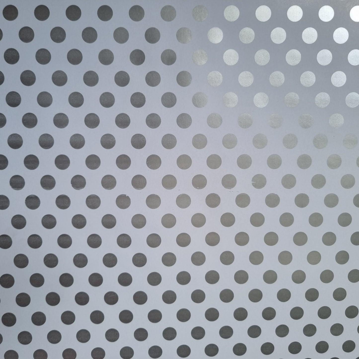 A close-up view of white wrapping paper with metallic silver polka dots.