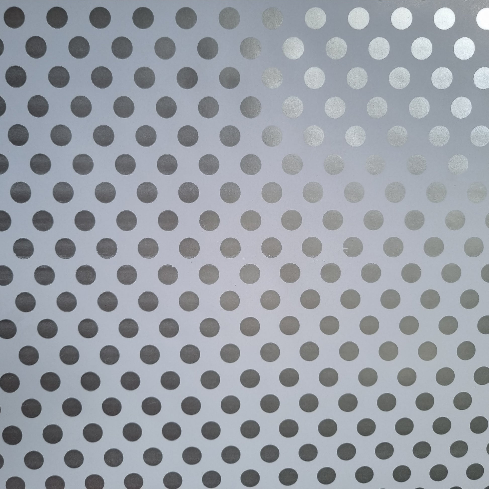A close-up view of white wrapping paper with metallic silver polka dots.