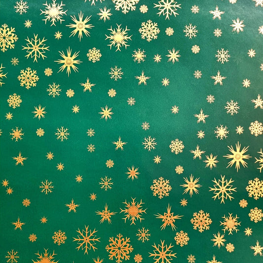 A roll of green wrapping paper with a pattern of small gold snowflakes.
