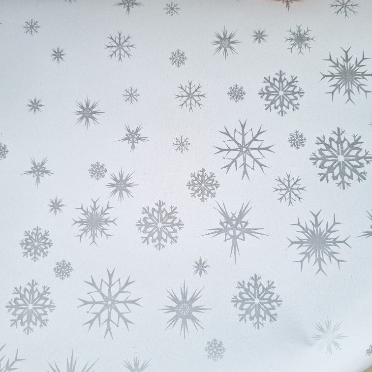 White wrapping paper with metallic silver snowflake patterns.