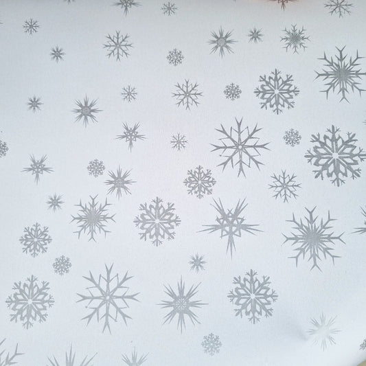 White wrapping paper with metallic silver snowflake patterns.